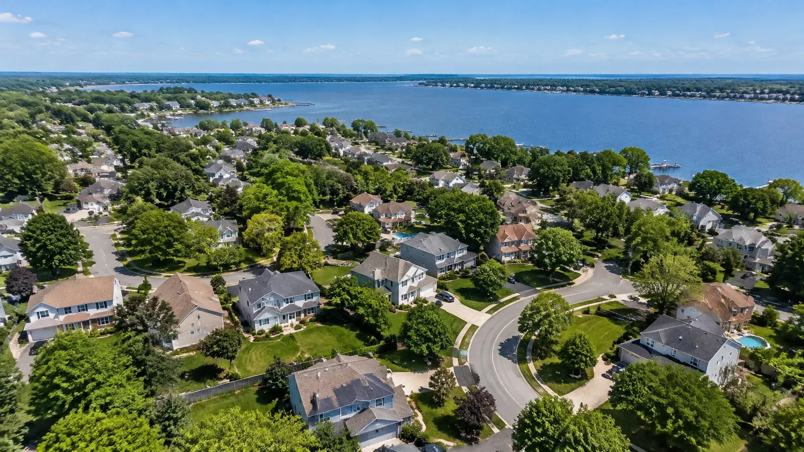 Aerial view of a suburban neighborhood of shingle-roofed homes beside a wide river